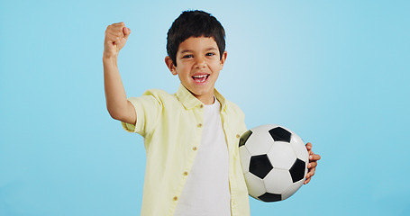 Image showing Winner, soccer ball or face of child in studio with smile, joy or happiness for sports success, score or goal. Happy boy, portrait or excited kid with fist or football on blue background mockup space