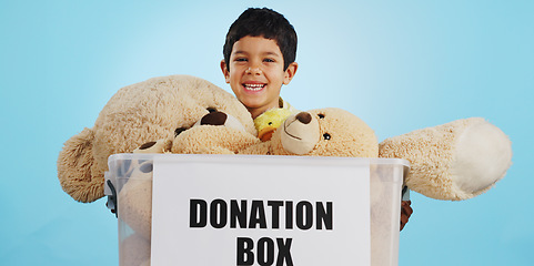 Image showing Boy in studio with toys, donation in box and smile for children, social charity and hope in kindness. Care, donate and happy kindergarten child with teddy bear package at kids ngo on blue background.