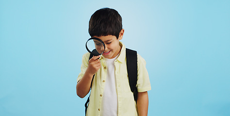 Image showing Search, looking and a child with a magnifying glass on a blue background for inspection or education. Studying, learning and a boy kid with tools for research, detective work or curious with a lens