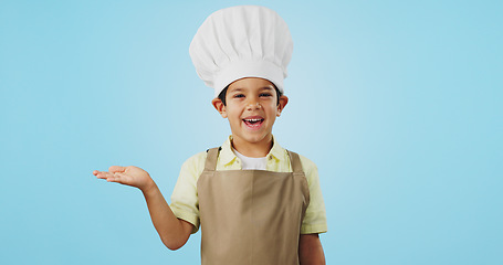 Image showing Child, happy face and chef hand to show promotion, advertising or deal in studio. Dress up, profession and young boy happy from future career of cooking and open palm for sale with blue background