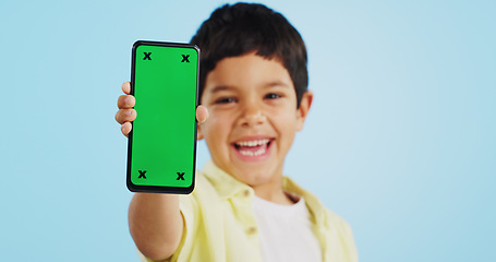 Image showing Happy child, face or phone green screen in studio on social media for ecommerce, tech or download app logo. Blue background, space or kid with notification for online marketing, mockup or advertising