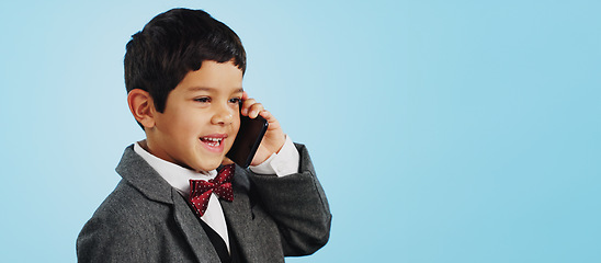 Image showing Child, talking and boy with phone call in studio, blue background and mockup with telephone chat or conversation. Calling, kid and speaking with cellphone communication or discussion with mobile