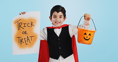 Image showing Halloween, poster and portrait of child with basket of sweets for candy isolated in studio blue background and happy. Holiday, laughing and kid in vampire costume for celebration in fantasy festival