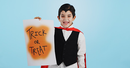 Image showing Halloween, poster and portrait of child with paper board for candy isolated in a studio blue background and happy. Holiday, laughing and kid in vampire costume for celebration in fantasy festival