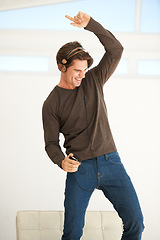 Image showing Dance, headphones and man with phone in home to celebrate freedom, enjoy happy subscription and hearing digital audio. Excited guy listening to music, radio and sound on mobile smartphone with energy