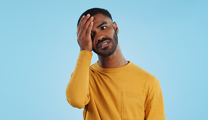 Image showing Stress, fail and man in studio with facepalm emoji for stupid mistake or regret on blue background. Anxiety, oops and male model with disaster, crisis or fake news shame, frustrated and unhappy