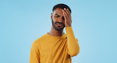 Image showing Stress, fail and man in studio with facepalm emoji for stupid mistake or regret on blue background. Anxiety, oops and male model with disaster, crisis or fake news shame, frustrated and unhappy