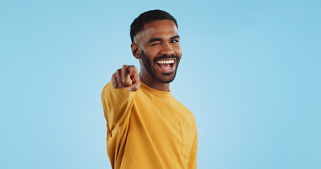 Image showing Face, wink and man with hand pointing at you in studio with choice, selection or offer on blue background. Opportunity, offer and portrait of male model with emoji for join us, deal or invitation