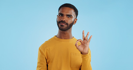 Image showing Happy, face and man with perfect hands in studio for support, review or success, vote or agree on blue background. Smile, portrait and male model show ok, emoji or yes, thank you or feedback results