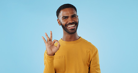 Image showing Happy, face and man with perfect hands in studio for support, review or success, vote or agree on blue background. Smile, portrait and male model show ok, emoji or yes, thank you or feedback results