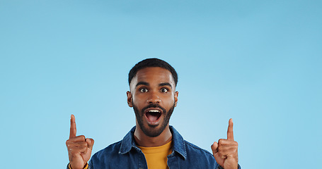 Image showing Happy man, pointing and news announcement with portrait in studio, surprise emoji and advertising. Mockup, mexican person and smiling in casual fashion for offer and notification by blue background