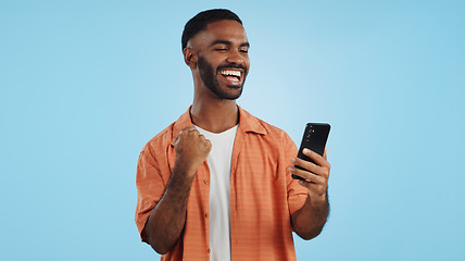 Image showing Man, fist celebration and phone in studio for esports, gambling and profit with trading by blue background. African person, investor and smartphone with fintech app, lotto and revenue on stock market