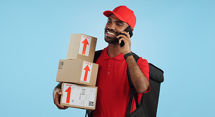 Image showing Man, logistics and courier with cellphone in communication to client, delivery or boxes in studio. Indian person, supply chain and cargo in conversation with customer, packages and blue background