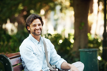 Image showing Travel, relax and portrait of a man on a park bench for a break, morning commute or summer. Smile, nature and a young person or tourist in a public garden for tourism, sightseeing or a vacation