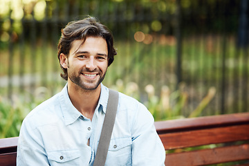 Image showing Happy, relax and portrait of a man on a park bench for a break, morning commute or travel. Smile, nature and a young person or tourist in a public garden for tourism, sightseeing or a vacation