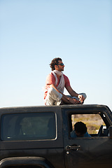 Image showing Road trip, man and sitting on car roof for scenery, nature and fresh air on adventure or vacation in South Africa. People, tourist or traveler on rooftop of van with sunglasses for view or journey