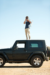 Image showing Photographer, man and camera on jeep outdoor for road trip, adventure or journey on rooftop with travel. Person, photography or memories for vacation, holiday or scenery in Asia or blue sky in nature