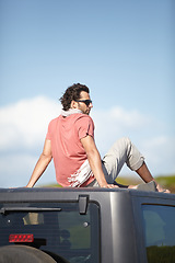 Image showing Road trip, man and sitting on van roof for scenery, nature and fresh air on adventure or vacation in South Africa. People, tourist or traveler on rooftop of van with sunglasses for view or journey