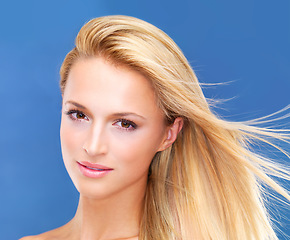 Image showing Portrait, beauty and wind of a woman closeup in studio on a blue background for natural wellness or cosmetics. Face, skincare and shampoo for hair with a young model at the salon for dermatology