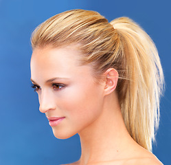 Image showing Face, beauty and hair of a woman closeup in studio on a blue background for skin wellness or cosmetics. Aesthetic, skincare and ponytail with a young model profile at the salon for dermatology