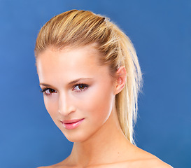 Image showing Portrait, beauty and ponytail of a woman closeup in studio on a blue background for skin wellness or cosmetics. Face, skincare and cosmetics with a natural young model at the salon for dermatology