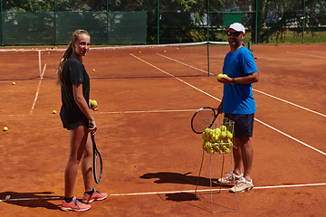 Image showing A professional tennis player and her coach training on a sunny day at the tennis court. Training and preparation of a professional tennis player