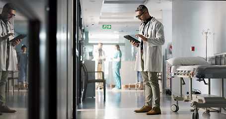 Image showing Doctor, man and tablet with reading, corridor and planning for surgery, advice or check in hospital. Medic, touchscreen and typing with contact, app or brainstorming for medical innovation in clinic