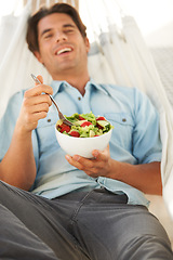 Image showing Happy, man and eating a healthy salad in a hammock for travel, freedom and wellness, diet or detox on vacation. Food, brunch and cheerful male vegetarian with vegetable meal outdoor for nutrition