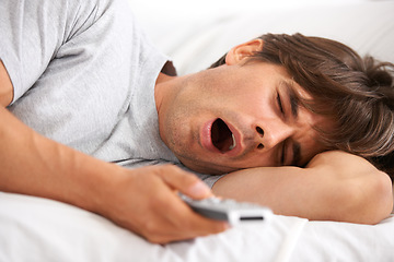 Image showing Tv, yawn and tired man in bed with remote control for streaming movies in his home. Fatigue, relax and morning lazy male in a bedroom with television, show or film while on vacation in his house