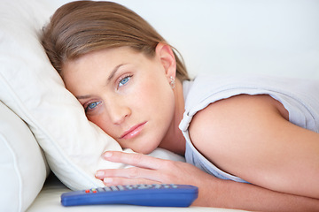 Image showing Depression, relax and a woman watching tv on a sofa in the living room of her home for entertainment. Face, sad and remote with a young person streaming a video, movie or film in her apartment