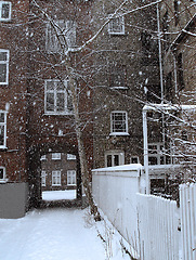 Image showing Winter, snow and storm in a village apartment, real estate or buildings with landscape or neighborhood. Cold weather, environment or location in russia outdoor in nature with ice, tree or brick house