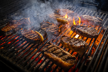 Image showing Steaks cooking over flaming grill