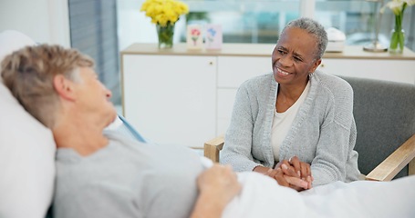 Image showing Senior women friends, hospital bed and holding hands with conversation, care and support for recovery from surgery. Clinic visit, empathy and elderly lady with smile, chat and listen with solidarity