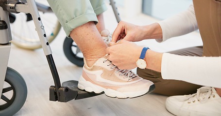 Image showing Caregiver, help and senior woman in wheelchair with shoes in closeup for comfort, care. Nurse, hand and sneakers for elderly person with disability in retirement home for support with medical worker.