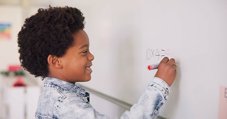 Image showing Math class, happy child at board for education, learning and problem solving for skill development. Boy writing on whiteboard in classroom with solution, thinking and smile at school for knowledge.
