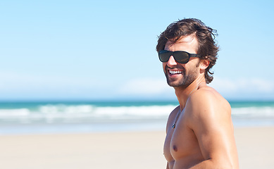 Image showing Nature, sunglasses and laugh or a man on the beach for travel, freedom or adventure on vacation. Summer, space and a young person shirtless by the ocean or sea on a tropical coast for holiday