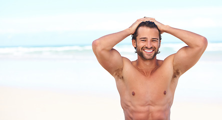 Image showing Portrait, smile and space with a man on the beach in summer for travel, freedom or adventure on vacation. Sea, body and a happy young person shirtless on the sand with a blue sky on a tropical shore