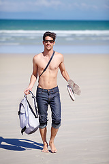 Image showing Portrait, walking and the body of a man on the beach for travel, freedom or adventure on vacation. Summer, sand and sunglasses with a young person shirtless by the ocean or sea for a coastal holiday