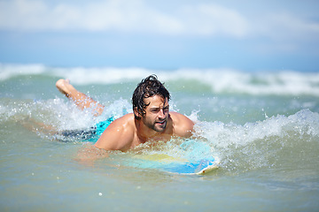Image showing Man, surfing and sea swimming with workout, training and waves with water sport and exercise outdoor of athlete. Surfer, freedom and vacation by the ocean and beach for summer wellness and fitness