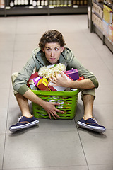 Image showing Man, grocery shopping and market, stress about inflation and expensive food, overwhelmed in supermarket. Groceries in basket, retail and customer shocked by price, choice and purchase with fear