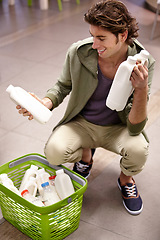 Image showing Man, milk and product comparison in grocery store, choice or shopping basket selection. Male person, smile and dairy drink for supermarket decision, expiry date information or reading nutrition value