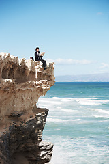 Image showing Reading, cliff and business man by ocean for freedom, holiday and vacation to relax in nature. Professional, mockup and corporate worker on rocks with book for calm mindset, ideas and future goals