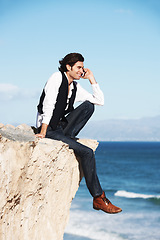 Image showing Cliff, edge and man with a happy phone call at the ocean, beach or connection on vacation, travel or social media. Businessman, contact and edgy chat on cellphone, communication or talking above sea