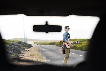 Image showing Musician, travel and man with a guitar on a road trip, journey or playing instrument in countryside on highway. Guitarist, trekking and guy waiting outdoor on street for a car, van or transportation