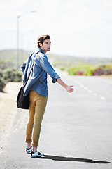 Image showing Man, travel and musician with a guitar on a road trip, journey or tour in the countryside on highway. Guitarist, trekking and portrait of guy waiting on street for a car, van or transportation