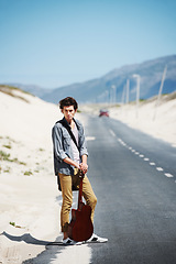 Image showing Musician, travel and man with a guitar on a road trip, journey or tour in the countryside on highway. Guitarist, trekking and portrait of guy waiting on street for a car, van or transportation