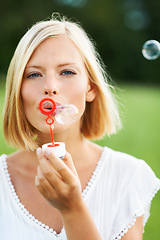 Image showing Woman, portrait and blowing bubbles in nature for fun day or playing at outdoor park. Face of young happy female person or blonde with stick or wand to blow bubble on playful holiday or summer break