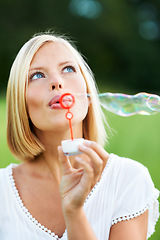 Image showing Woman, thinking and blowing bubbles in nature for fun day or playing at outdoor park. Face of female person or blonde in wonder with stick or wand to blow bubble on playful holiday or summer break