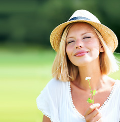 Image showing Woman, park and peace with thinking, flower and eyes closed with peace, relax and memory outdoor in summer. Girl, garden or backyard with plant, scent and smile for spring in countryside with hat