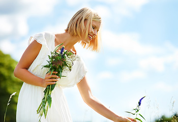 Image showing Happy, woman and picking flowers in a garden with freedom, fun and peace in the countryside. Smile, adventure and female person with nature, bouquet or fresh floral bunch on a field while traveling